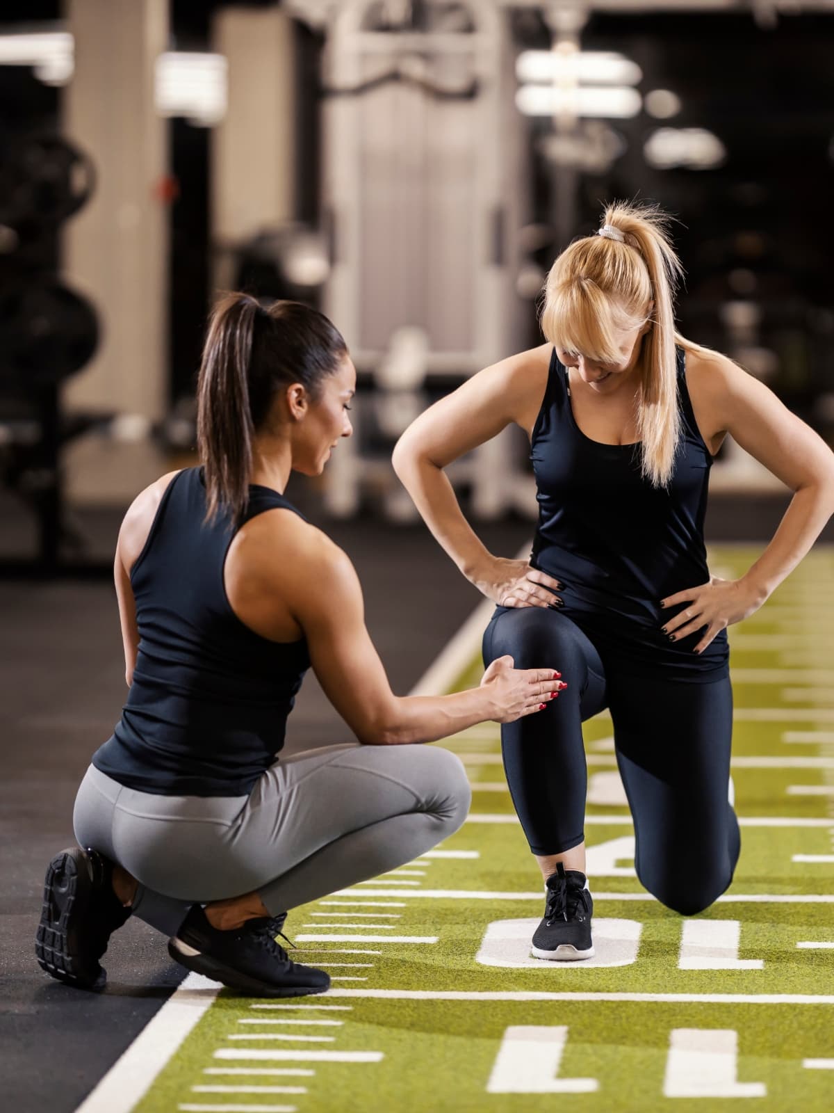 Physiotherapist helping a person with rehabilitation exercises on a gym floor